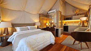 Ein Zeltraum mit Bett, Nachttischen, Schreibtisch, Stuhl und einer Küchenzeile.