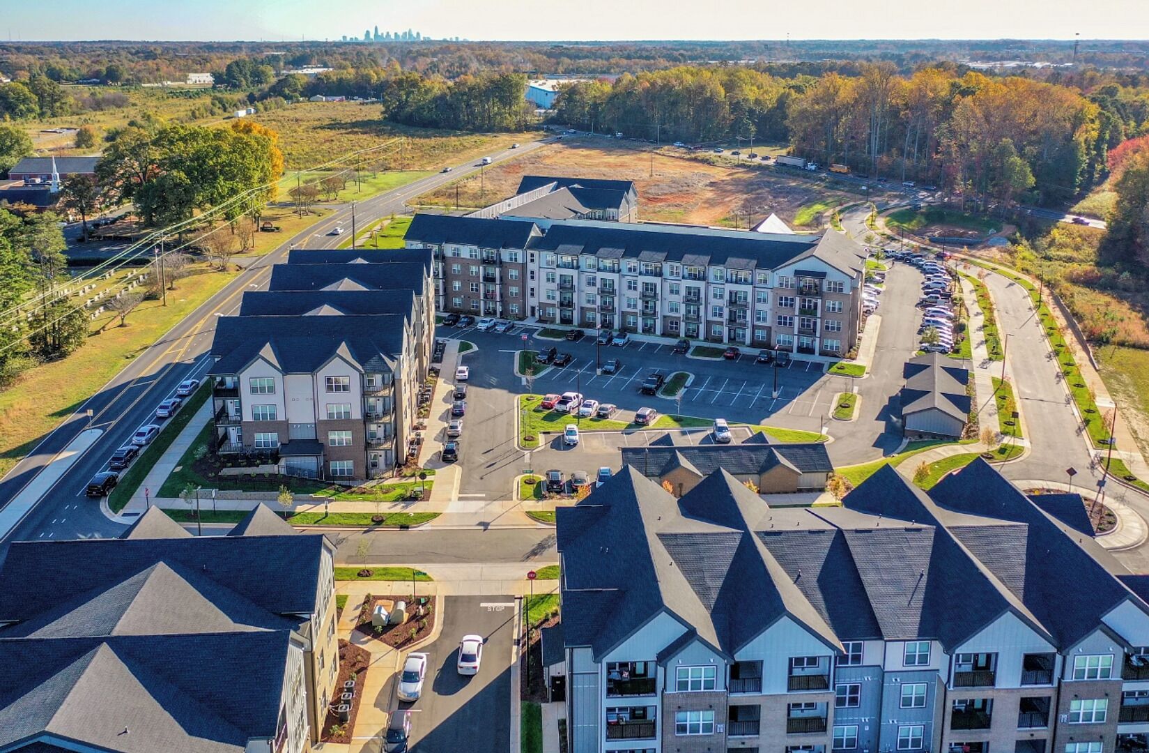 A multi-story residential building with a parking lot and a road in the foreground.