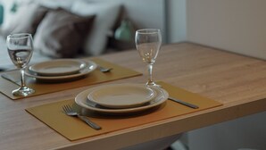 A dining table set with plates, cutlery, and wine glasses, with a sofa and wall art in the background. - Gente del Sur - Buena Vista (Ushuaia)