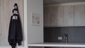 A modern kitchen with wooden cabinets, a white countertop, and three white bar stools. - Gente del Sur - Buena Vista (Ushuaia)