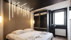 A modern hotel room with a large bed, built-in wardrobe, bedside table, and a window with a view. - L'Esplanade ⭐️⭐️⭐️⭐️ (Metz)