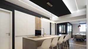 A modern kitchen with a central island, bar stools, and a dining area with a table and chairs. - L'Esplanade ⭐️⭐️⭐️⭐️ (Metz)