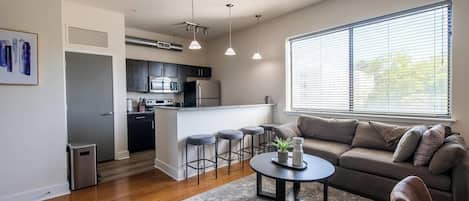 A modern kitchen with dark cabinets, a central island, and pendant lighting.