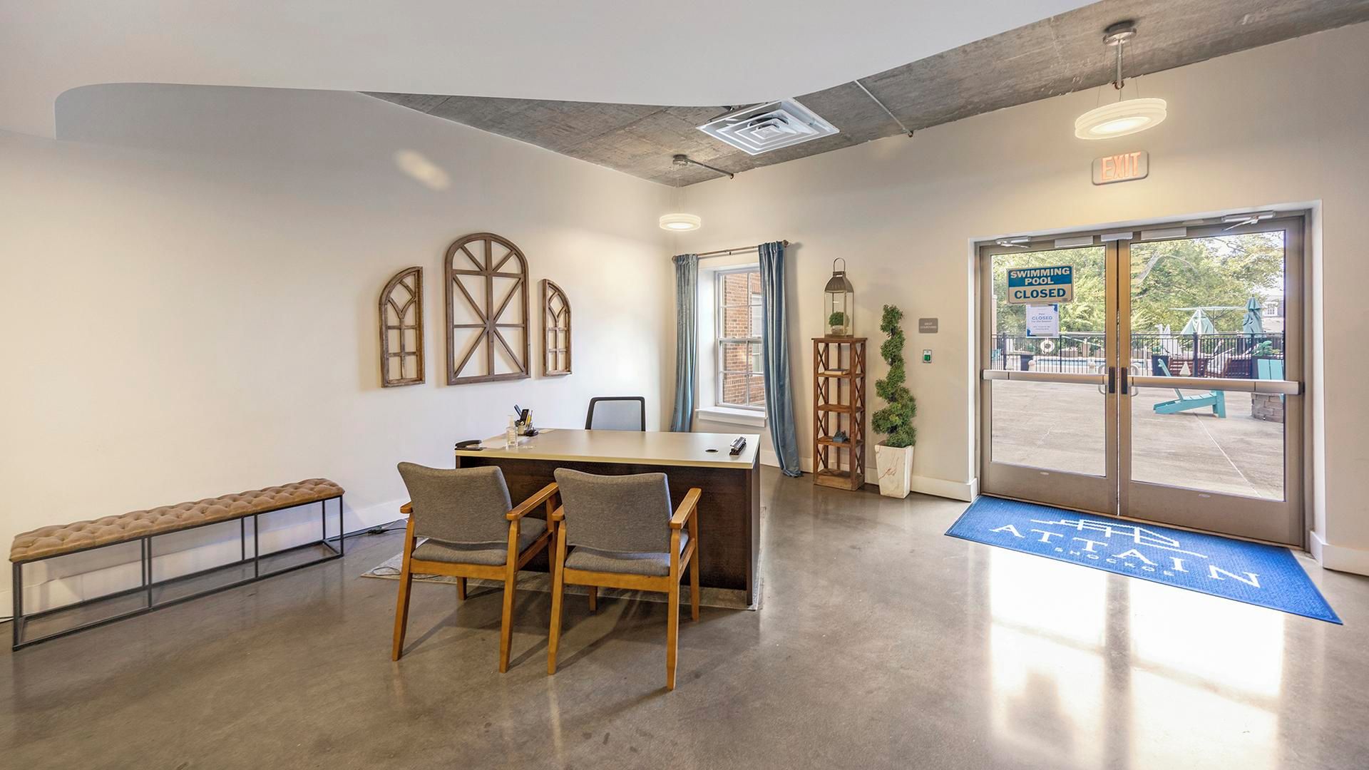 Una sala de conferències amb una taula llarga, dues cadires, una banca i un gran finestral amb vista a la zona de piscina exterior.