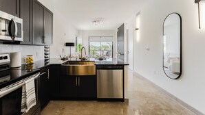 A modern kitchen with dark cabinetry, stainless steel appliances, and a central island.
