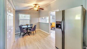 Una cocina moderna con un refrigerador de acero inoxidable, una mesa de comedor de madera con sillas y un ventilador de techo.
