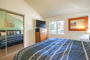 Ein Schlafzimmer mit einem Bett, einer Kommode und einem Fernseher auf einem Standfuß.