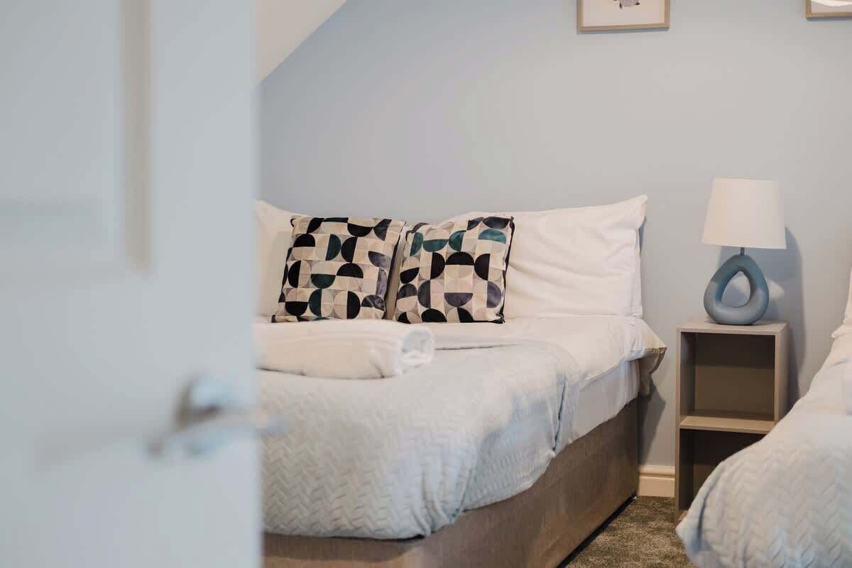 A bedroom with a bed, pillows, a bedside table, and a lamp.