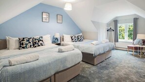A bedroom with two beds, a window with curtains, a hanging light fixture, and a small table with a chair. - Spacious 3 Bedroom House Sleeps 6 With WiFi (Bedford)