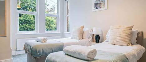 Una camera da letto con due letti, una finestra vista sul verde e un quadro appeso al muro.