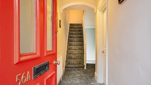 A red door with a mailbox, a staircase leading to an upper floor, and a white wall. - Spacious 3 Bedroom House Sleeps 6 With WiFi (Bedford)