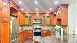 Una cocina con armarios de madera, electrodomésticos de acero inoxidable y encimera de granito.