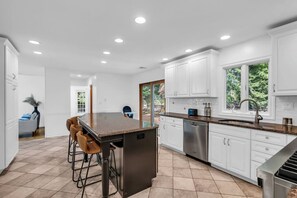A modern kitchen with white cabinets, a granite countertop, and a stainless steel dishwasher. - Group Spring Retreat | Fun Games & Gourmet Kitchen (Airmont)