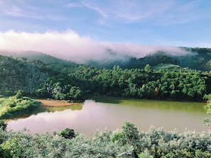A serene landscape with a lake surrounded by dense greenery and hills. - Chahill Dalat (Xuan Truong - Da Lat)