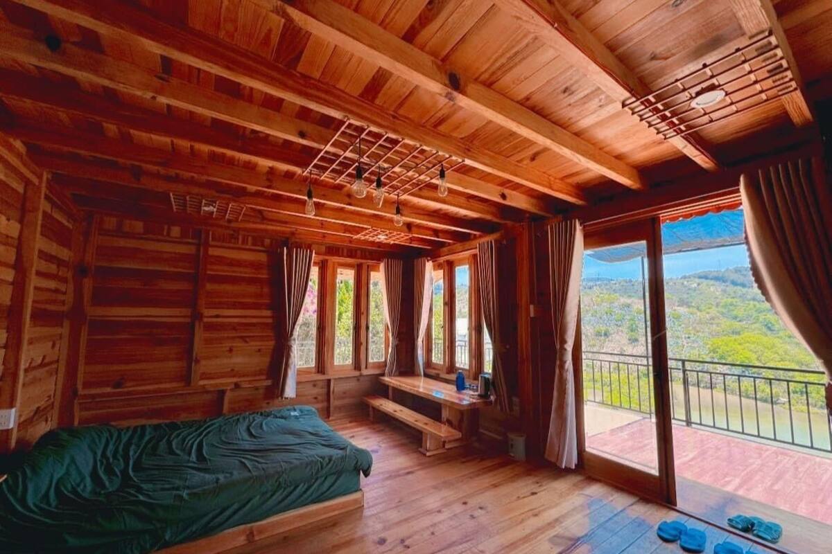 Una cabaña de madera con una cama, un banco y un balcón con vistas.
