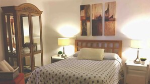 A neatly arranged bedroom with a bed, two bedside tables with lamps, a dresser, and a mirror. - Villa with pool in hotel zone (Cancún)