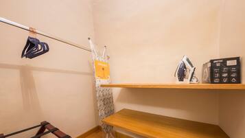 Rincón de una habitación con una estantería de madera, un perchero y un cortinero de ducha.