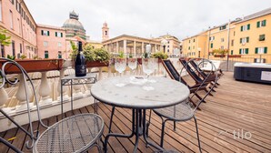 Une terrasse sur le toit avec une table ronde, des chaises et une bouteille de vin.