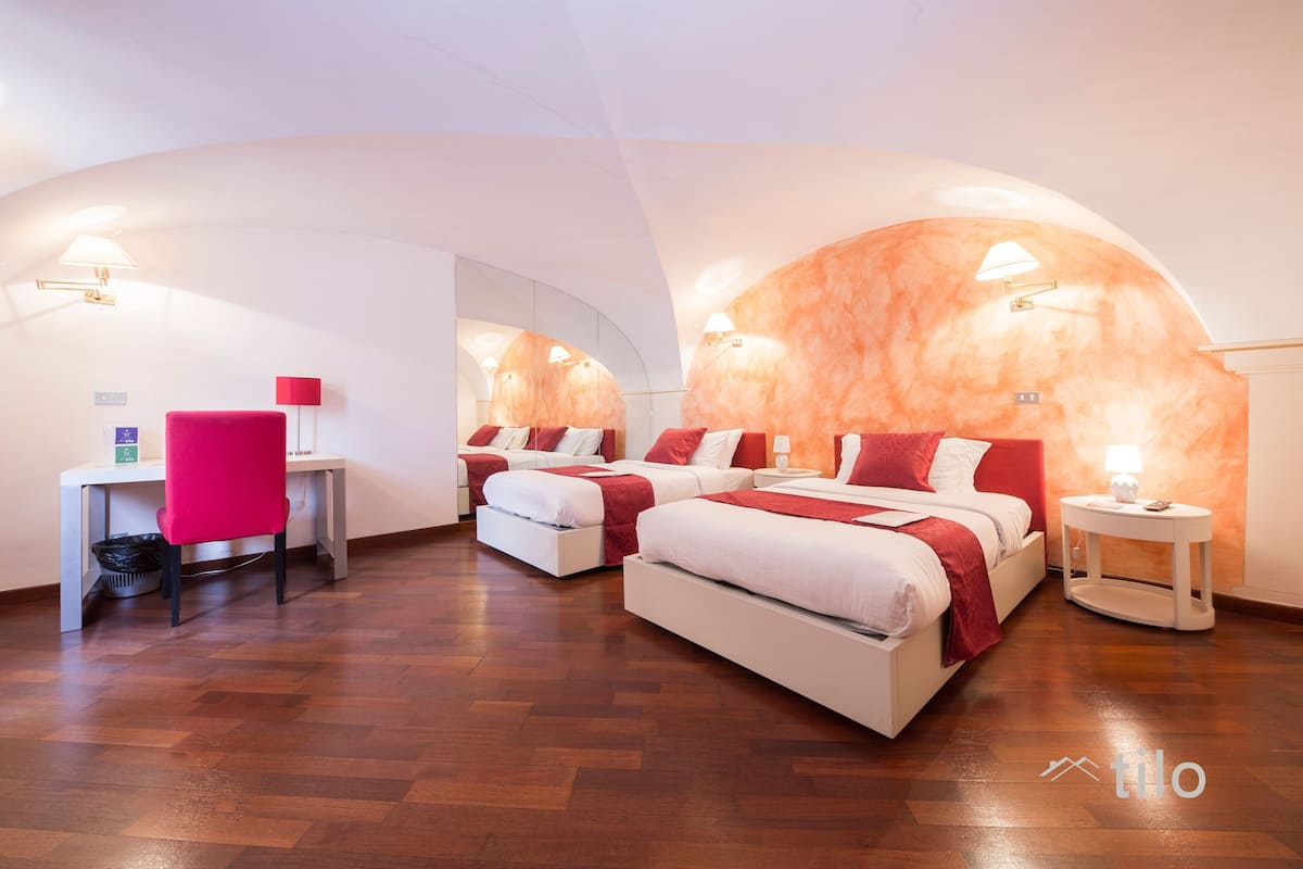 A modern hotel room with two beds, a desk, and a chair.