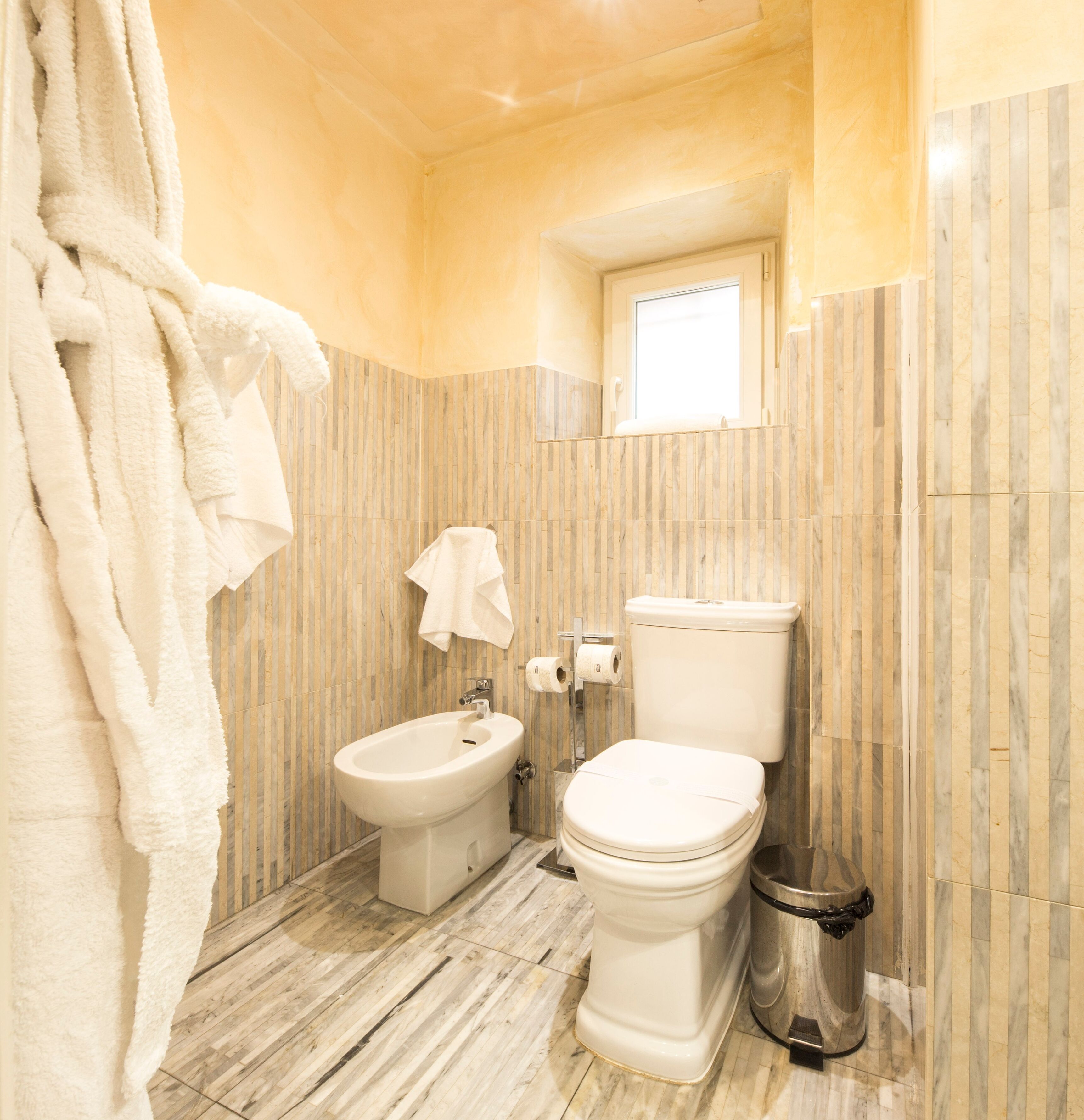 Un baño con bidé, inodoro y un cubo de basura.