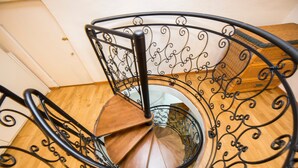 Un escalier en colimaçon avec des rampes en métal ouvragé et des marches en bois.