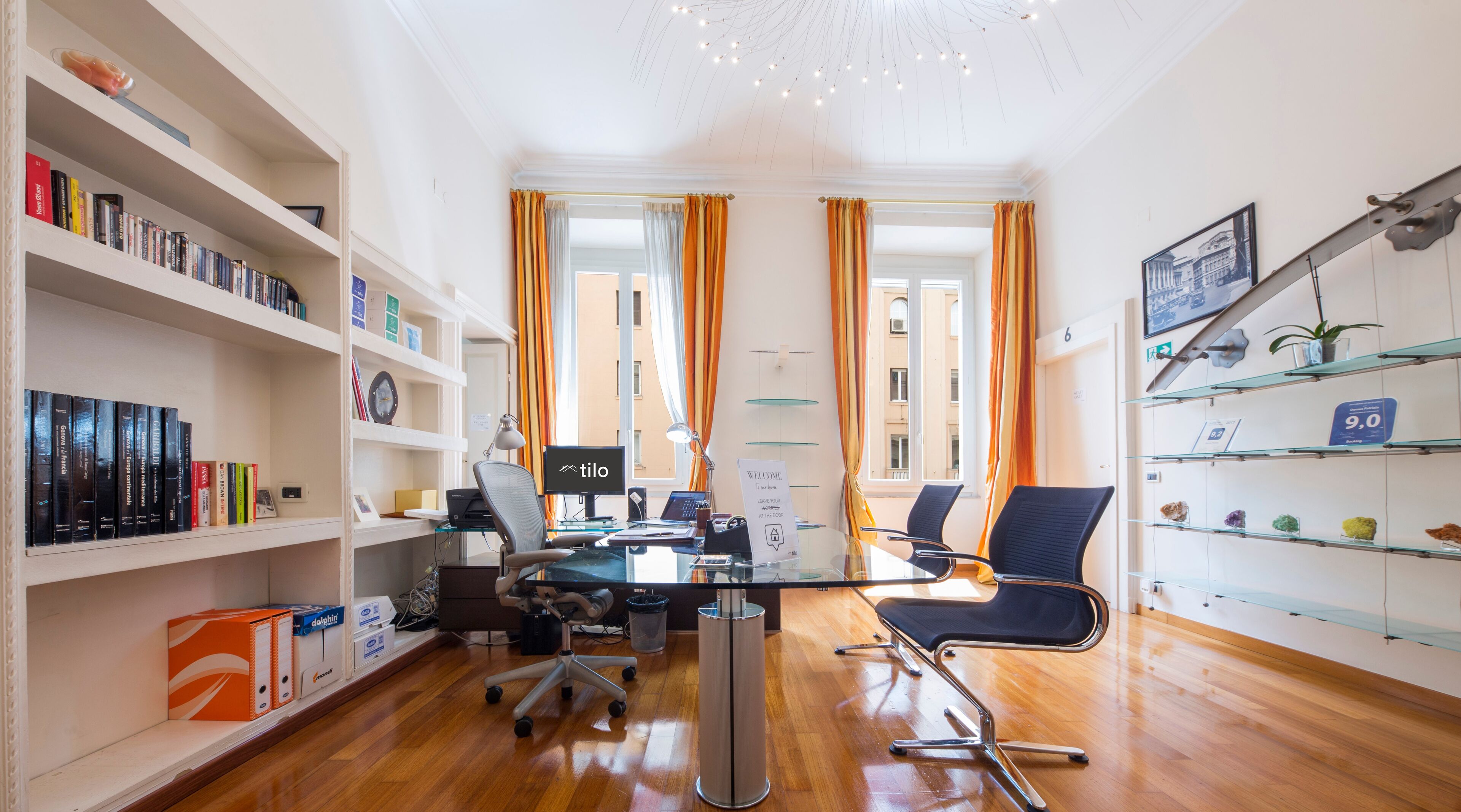Ein moderner Arbeitsplatz mit Schreibtisch, Computer und Stuhl. Links Bücherregale, rechts eine Pflanze.