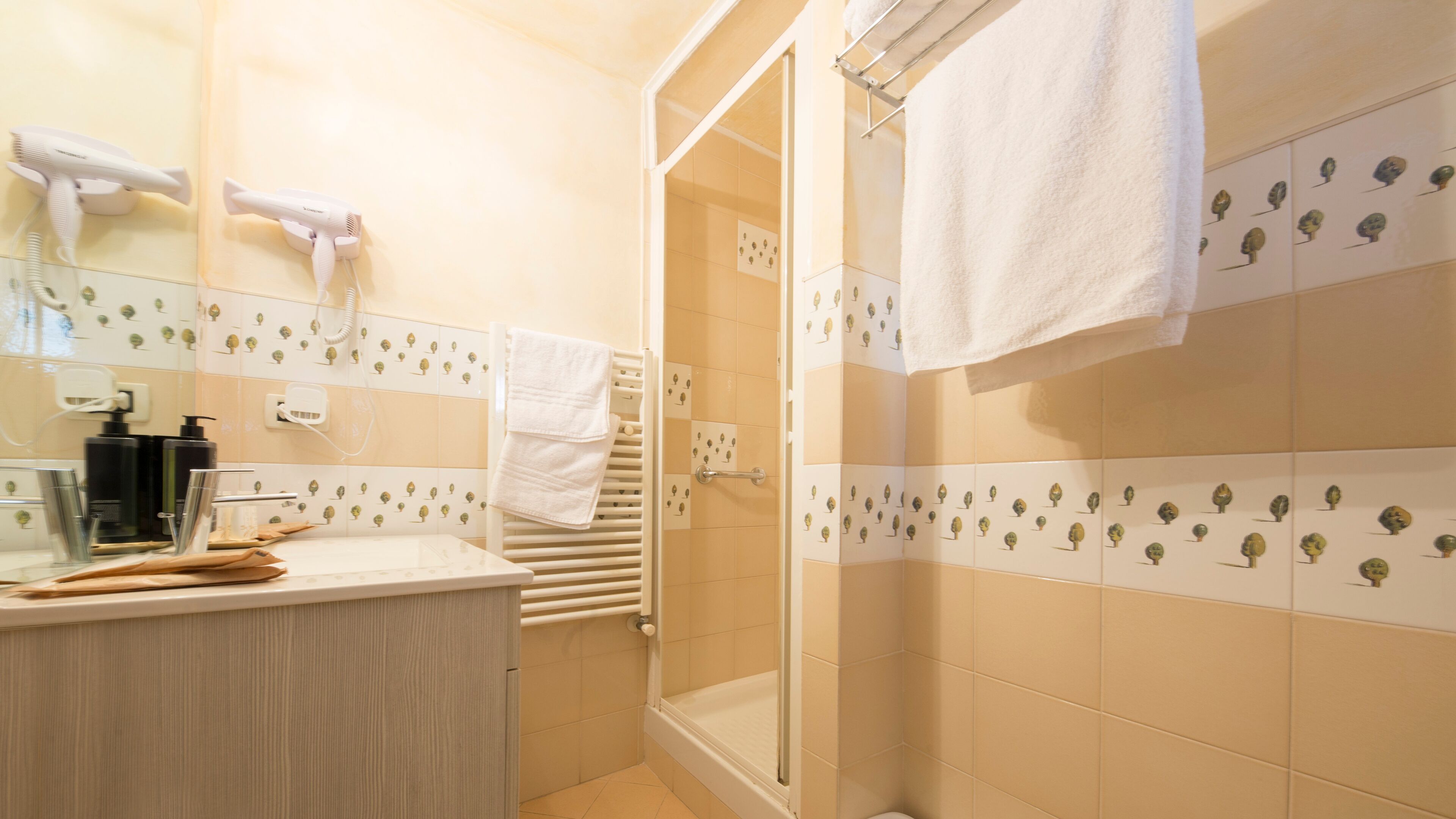 A bathroom with a shower, a sink with toiletries, and a towel rack.