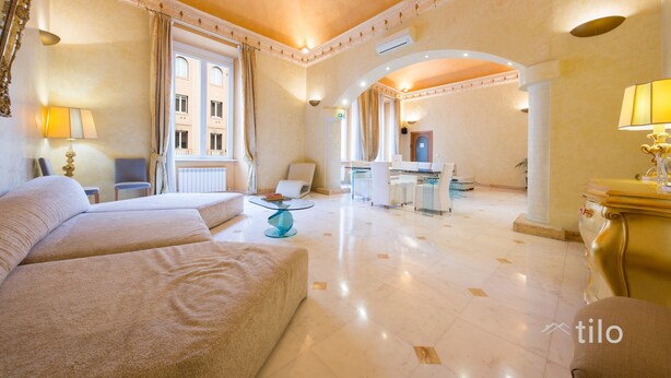 Un hall d’hôtel spacieux, doté d’un grand espace salon, d’un comptoir d’accueil et offrant une vue sur la façade de l’immeuble.