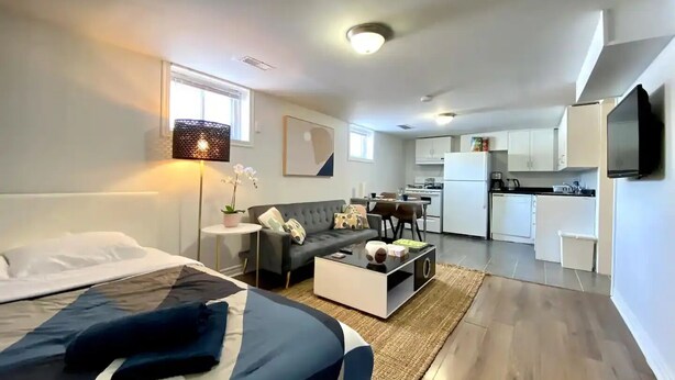 Ein modernes Apartment mit Bett, Sofa und einer kleinen Küchenzeile.