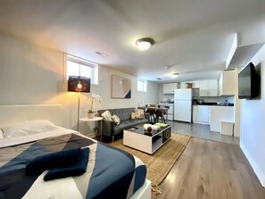 Un apartamento moderno con cama, sofá y una pequeña cocina.