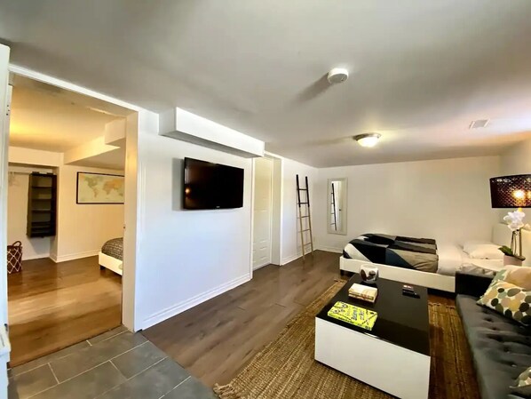 A modern living room with a flat-screen TV mounted on the wall, a sofa, a coffee table, and a lamp.