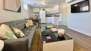 Ein modernes Wohnzimmer mit einer Couch, einem Couchtisch und einem Flachbildfernseher.