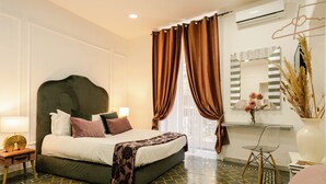 A modern hotel room with a large bed, a bedside table with a lamp, a chair, and a large mirror. - Naples Luxury Apartment, located in the historic center of Naples (Napoli)