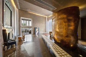 Enter a stylish lobby with a polished floor, a large sculpture, and a tufted bench.