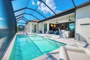 A swimming pool with clear water, surrounded by lounge chairs and a covered patio area. - VRCC - Villa Taradise (Cape Coral)