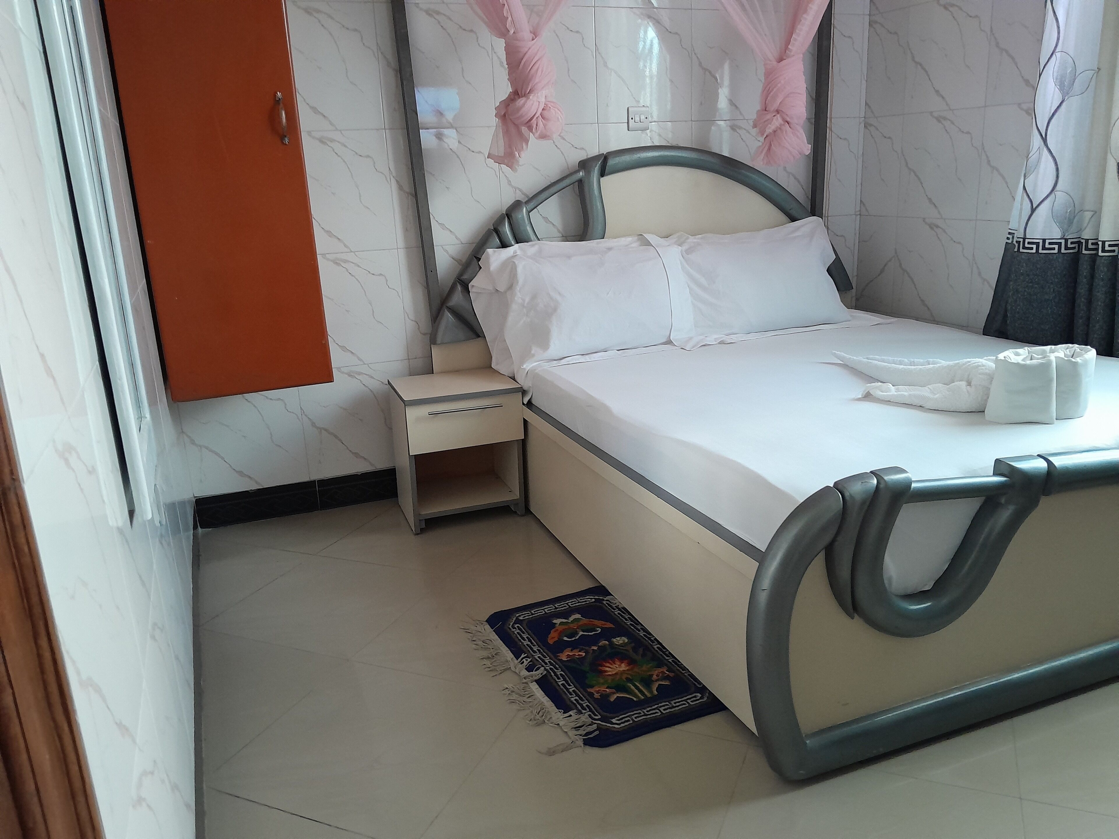 A neatly arranged bedroom with a bed, bedside table, and a small rug.