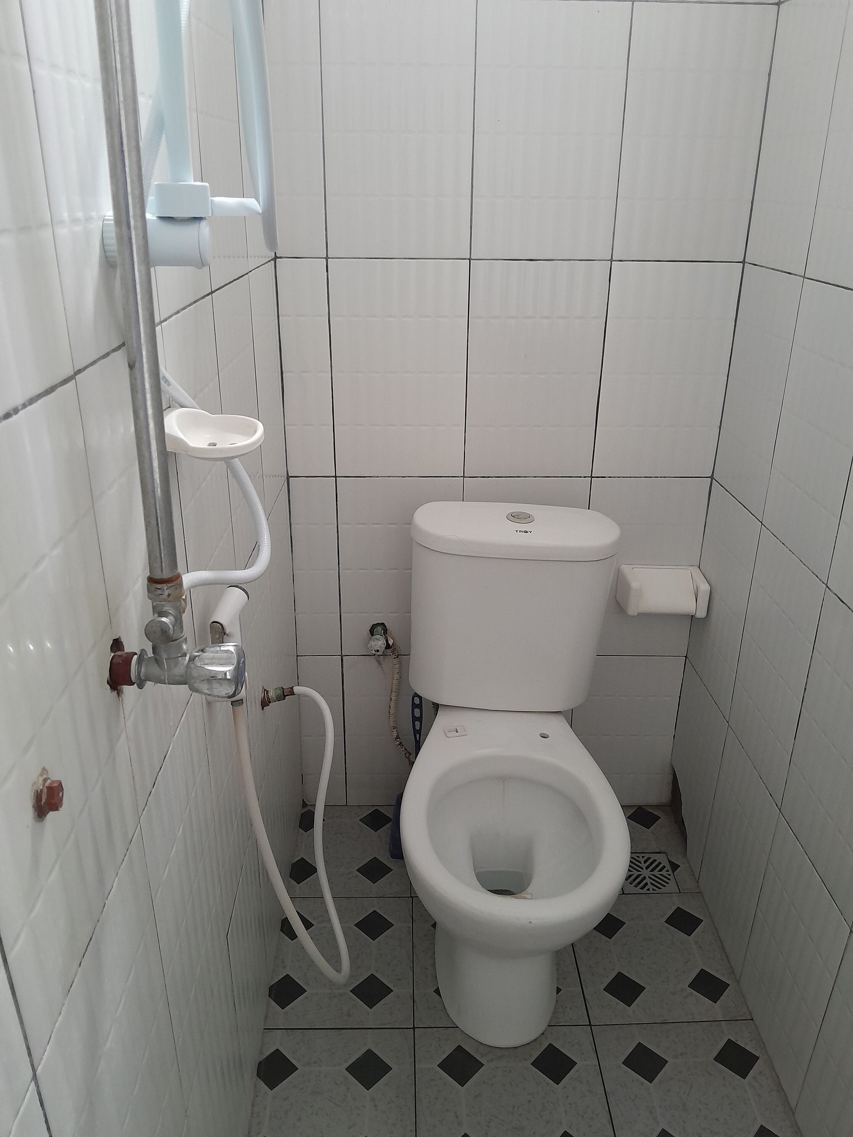 A small, tiled bathroom with a toilet, a bidet, and a shower.
