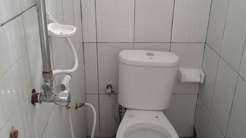 A small, tiled bathroom with a toilet, a bidet, and a shower.