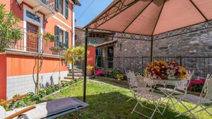 A patio with a table and chairs, surrounded by a garden with flowers and a stone wall. - Orazio Liberty House,Lunigiana, Nature (Fivizzano)