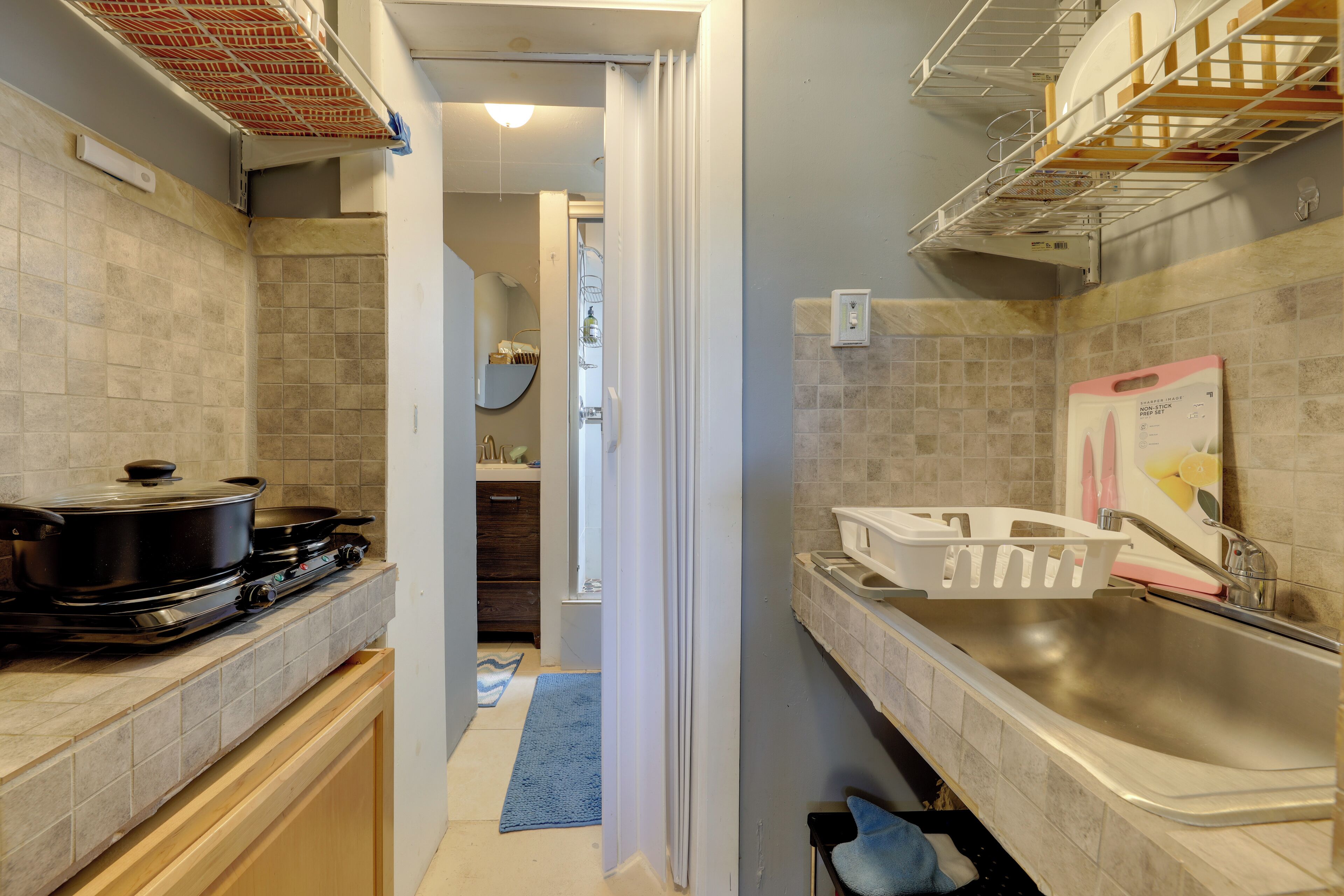 Una cocina compacta con estufa, pileta y estanterías.