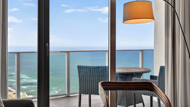 A balcony with wicker furniture, a table, and a lamp. - Bright & Stylish Stay at Splendid Resort - Prime Location and Stunning Views (Hollywood)