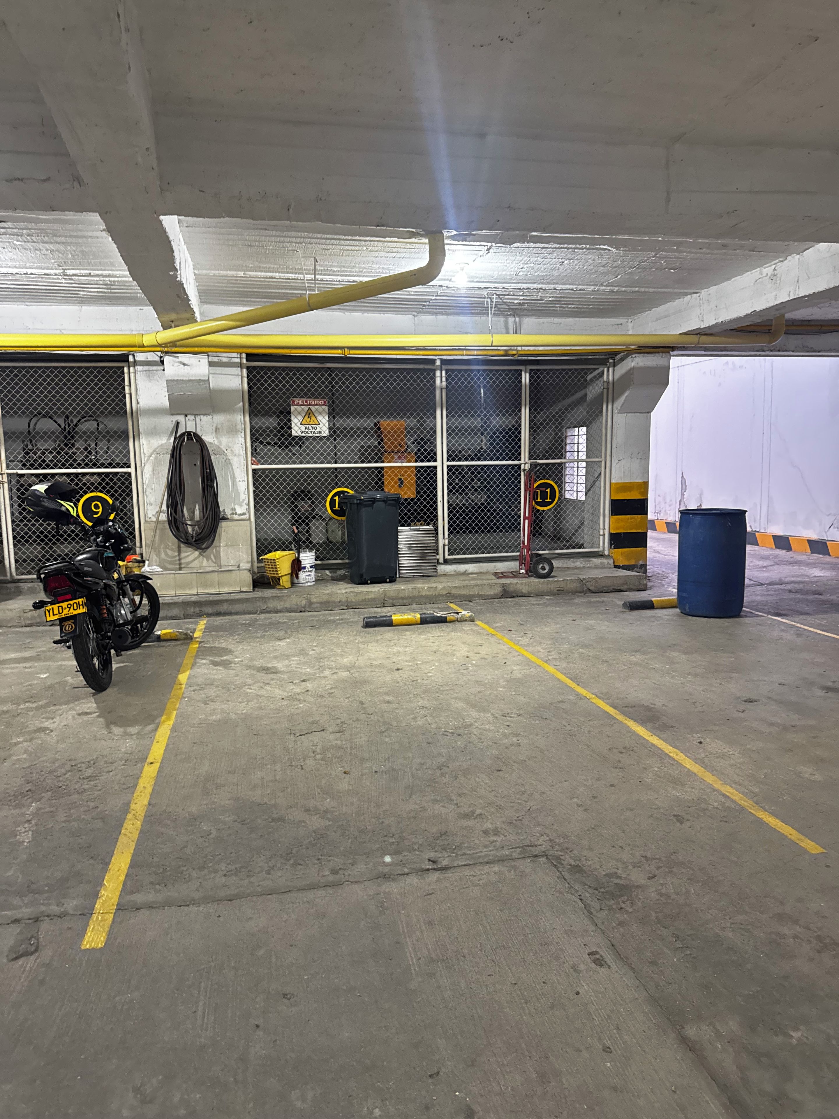 Een parkeergarage met betonnen vloeren, gele lijnen en een motorfiets op de voorgrond.