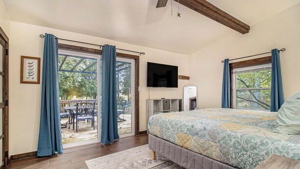 A bedroom with a bed, a television, and a view of the outdoors. - Wooded Retreat across from Lake MI (Manistee)