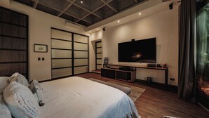 Ein modernes Schlafzimmer mit einem großen Bett, einem Fernseher auf einem Schrank und einem Schiebetürenkleiderschrank.