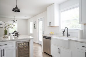 A modern kitchen with white cabinetry, a built-in dishwasher, and a wine cooler. - Comfy 3bd/2ba Cottage In The City of Atlanta (Atlanta)