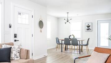 Una sala moderna con un sofá color beige, una mesa de comedor con cuatro sillas y una mesa de centro.
