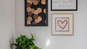A desk with a potted plant, framed artwork, and a quote on the wall.