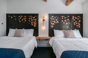 Ett hotellrum med två sängar, ett nattduksbord i trä och en väggmonterad lampa.