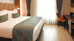 Een hotelkamer met een groot bed, een bureau met een laptop en een stoel.