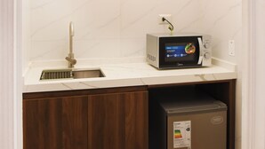 Een compacte keuken met een ingebouwde magnetron, een spoelbak en een kleine koelkast.